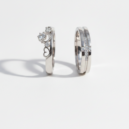 Two silver rings with clear gemstones displayed on a dark blue velvet ring box. One ring features a central round stone with smaller stones along the band, and the other is a slim band with a small cluster of stones.